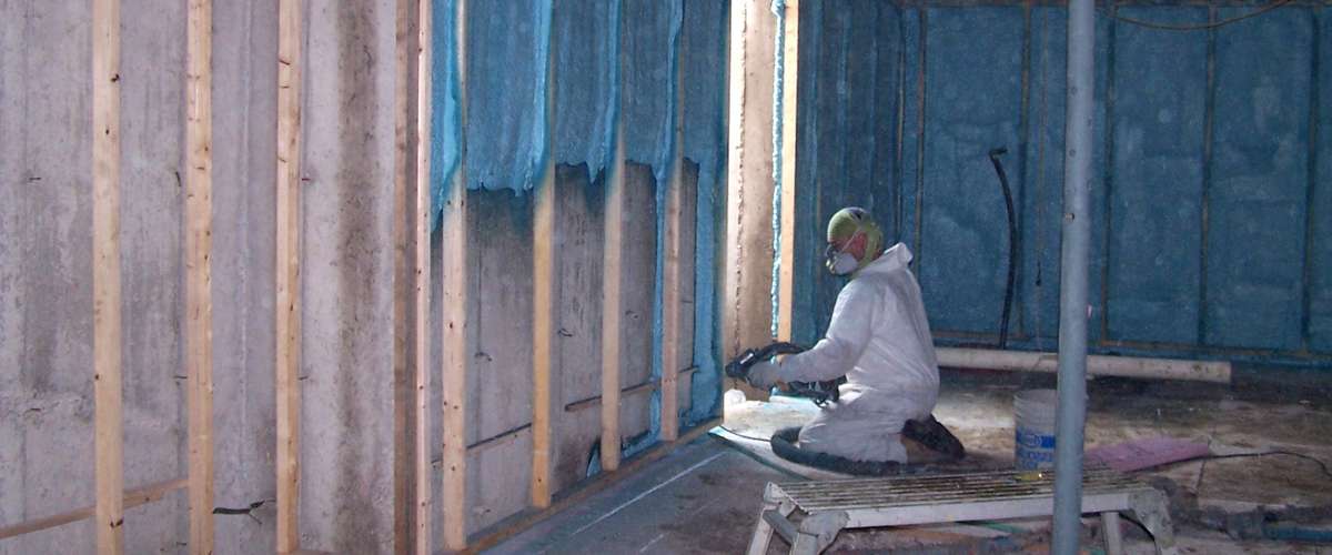 Closed cell spray foam insulation being applied to basement walls