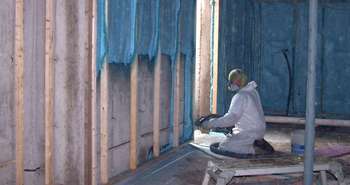 Closed cell spray foam insulation being applied to basement walls