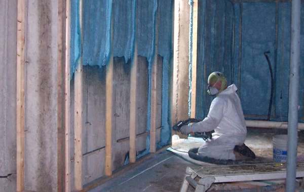 Closed cell spray foam insulation being applied to basement walls