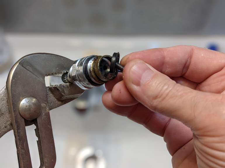 Flick the washer out of the faucet cartridge with the screw as you remove it