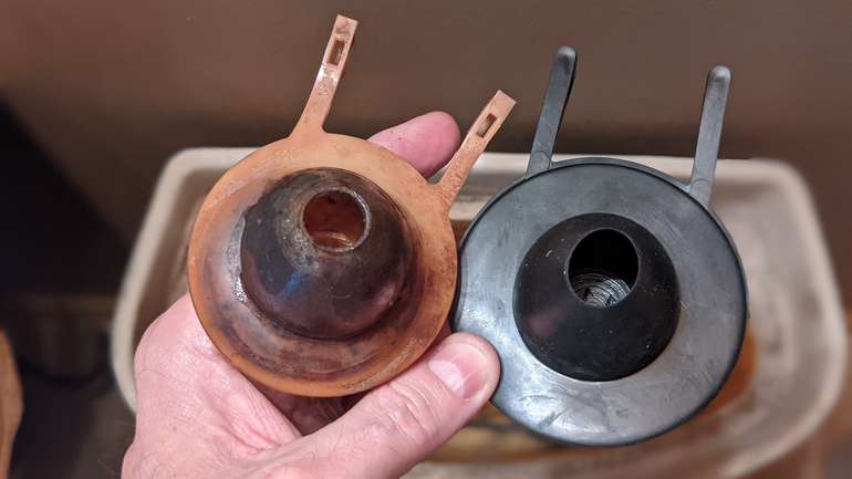 Comparing the old toilet flapper with the new replacement one - it's bigger